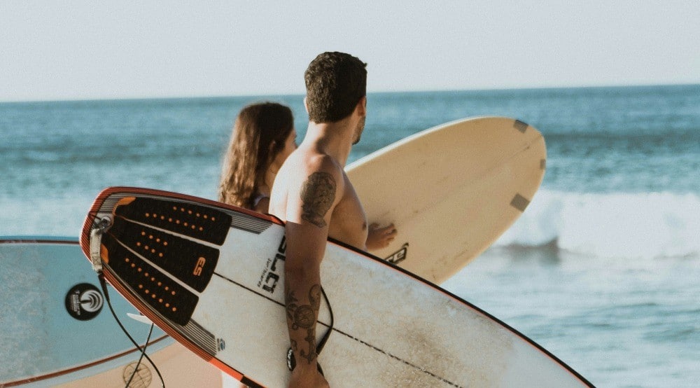 A couple walking with their surfboards at a Christian couples surf retreat