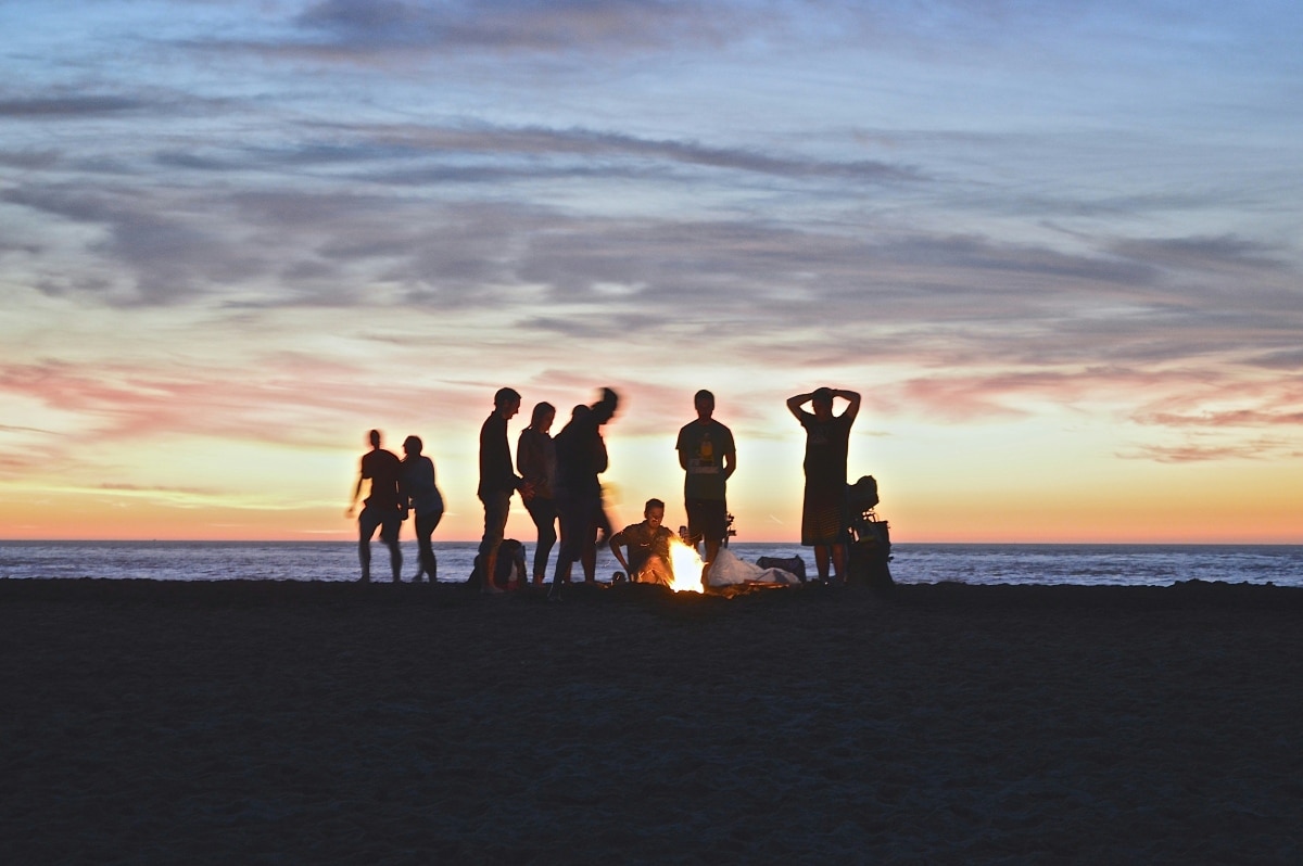 A group of people circled around a beach bonfire