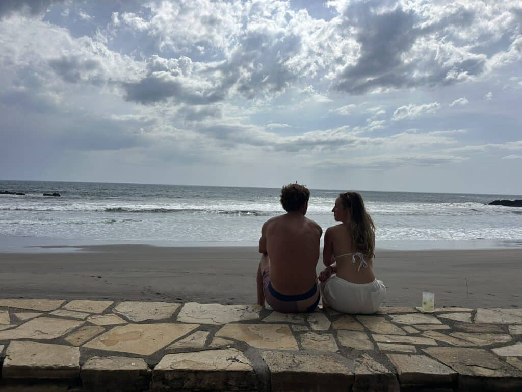 two people sitting on mandla beach at sunset
